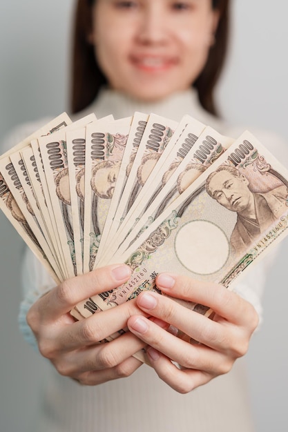 Mano de mujer sosteniendo la pila de billetes de yen japonés Dinero de mil yenes Japón efectivo Recesión fiscal Economía Inflación Finanzas de inversión y conceptos de pago de compras