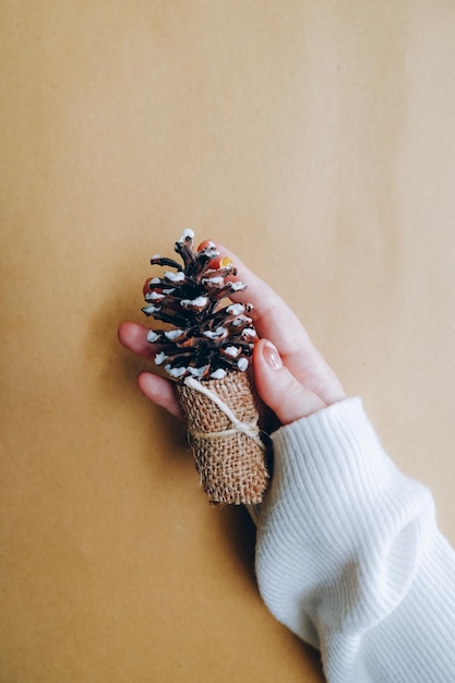 Mano de mujer sosteniendo pino decorativo hecho a mano de Navidad sobre fondo artesanal