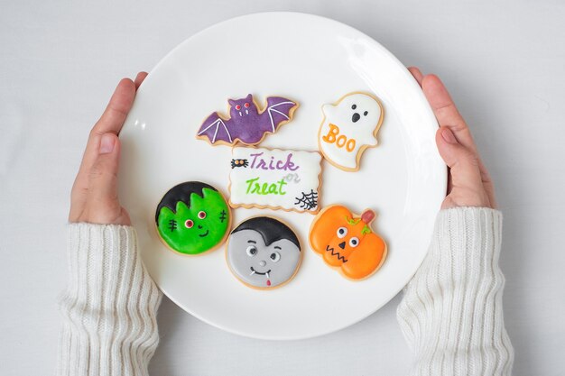 Mano de mujer sosteniendo la placa de divertidas galletas de Halloween. Feliz día de Halloween, truco o amenaza, hola octubre, otoño otoño, concepto tradicional, fiesta y vacaciones