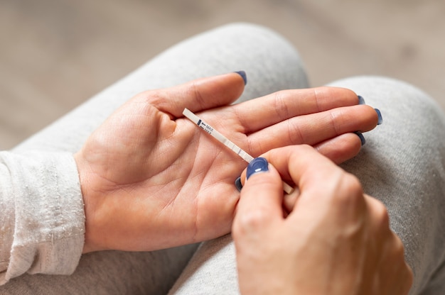 Foto mano de mujer sosteniendo una prueba de embarazo positiva