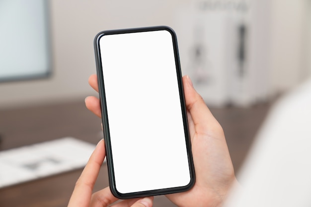 Mano de mujer sosteniendo smartphone y tocando la pantalla en blanco.