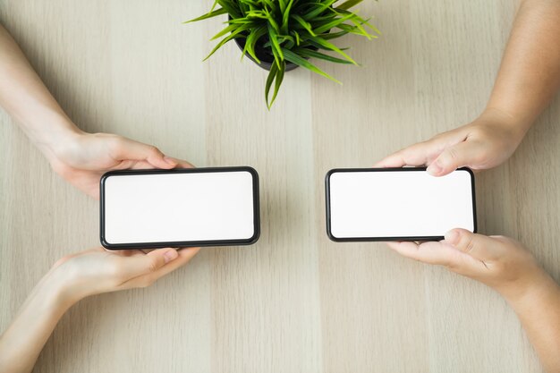 Foto mano de mujer sosteniendo smartphone y tocar la pantalla en blanco.