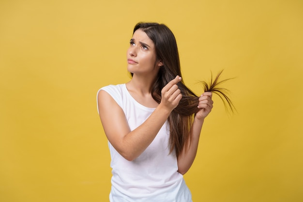 Mano de mujer sosteniendo su cabello largo con mirar las puntas divididas dañadas de los problemas de cuidado del cabello.