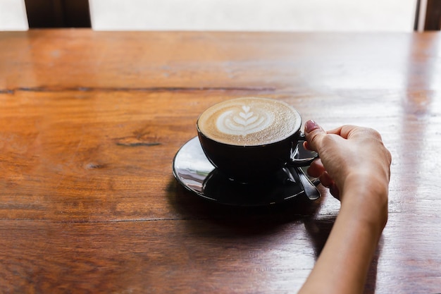 Mano de mujer sosteniendo una taza de café en la cafetería