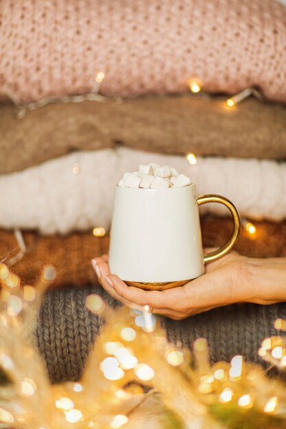 Mano de mujer sosteniendo una taza de chocolate caliente con malvaviscos