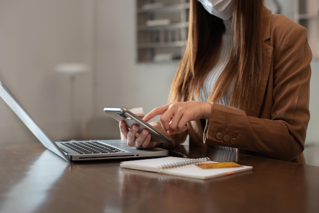 Mano de mujer sosteniendo teléfono inteligente y computadora portátil usando tarjeta de crédito para compras en línea Concepto de compras en línea