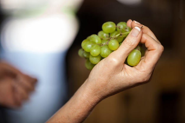 Mano de mujer sosteniendo uvas