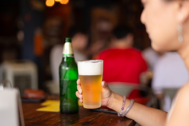 Mano de mujer sosteniendo un vaso de cerveza fría de vacaciones.