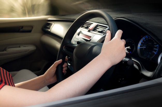 Mano de mujer sosteniendo el volante negro