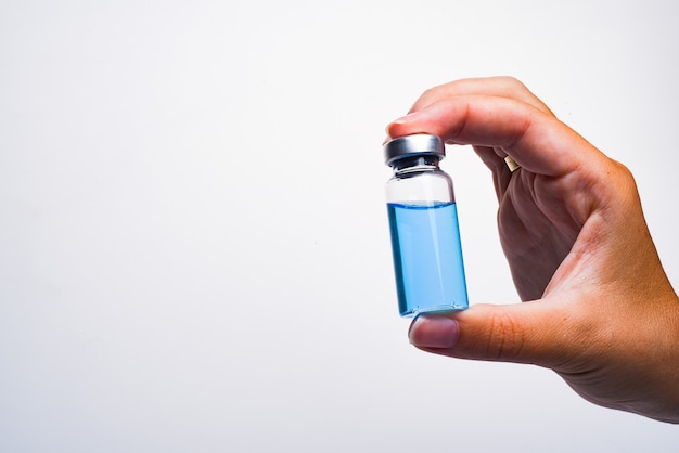 La mano de una mujer sostiene una ampolla. Vacuna. La ampolla con el medicamento. Medicación inyectable.