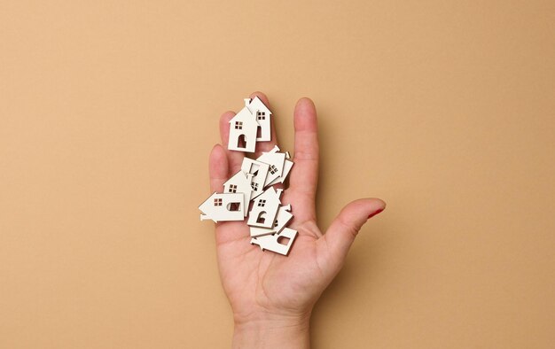 Foto la mano de la mujer sostiene casas de madera en miniatura concepto de búsqueda de bienes raíces para alquilar hipotecas reales e