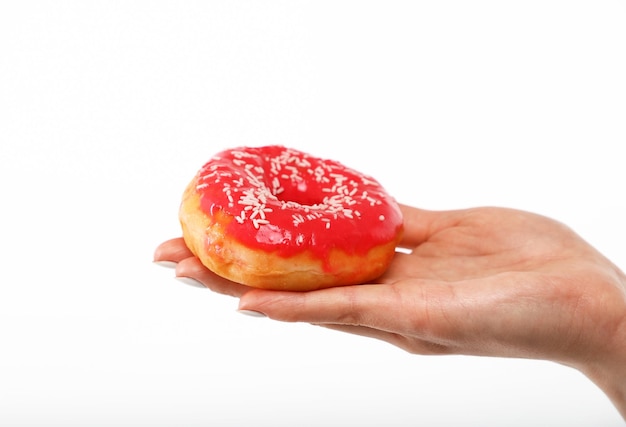 Mano de mujer sostiene donut rojo sobre blanco