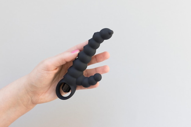 Mano de mujer sostiene juguete sexual sobre fondo gris Espacio de copia de primer plano