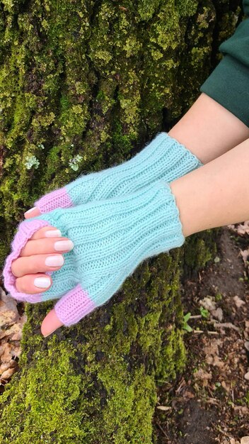 La mano de una mujer sostiene un par de guantes de punto azules.