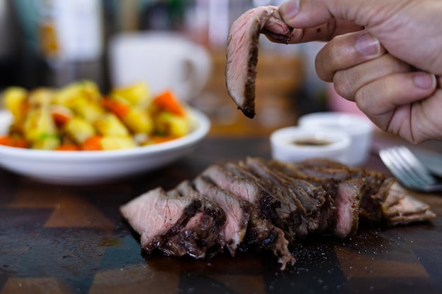 Foto la mano de la mujer sostiene pedazos de carne asada