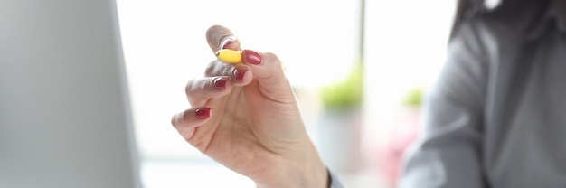 La mano de la mujer sostiene la pluma cerca del monitor de la computadora en los documentos de la mesa