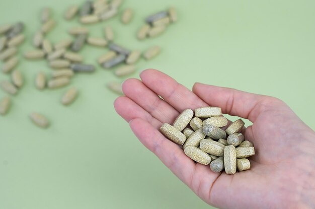 La mano de una mujer sostiene un puñado de pastillas verdes Fitness deporte y concepto de estilo de vida saludable Primer plano Vista superior Copiar espacio