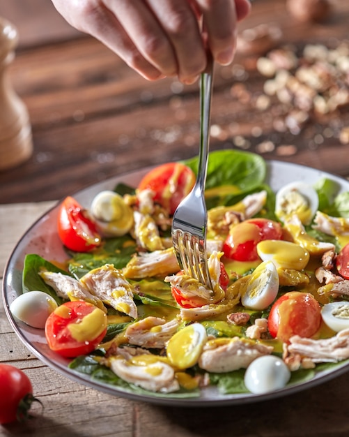 Foto mano de mujer sostiene un tenedor con ensalada vegetariana dietética recién preparada con orgánico natural