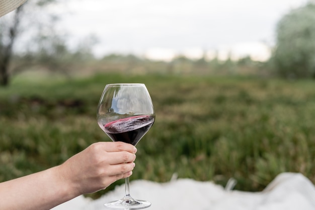 La mano de la mujer sostiene un vaso con vino tinto