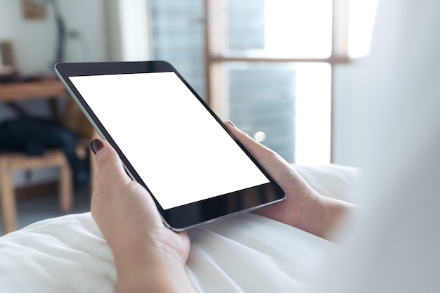 Mano de mujer con tablet pc en la cama