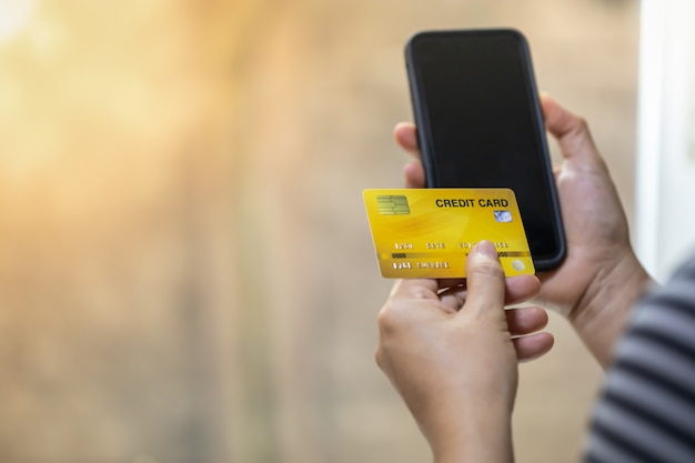 Mano de mujer con tarjeta de crédito y teléfono móvil inteligente con espacio de copia.