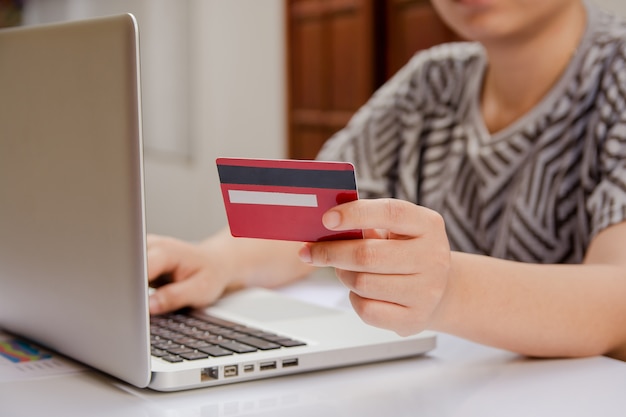 Mano de mujer con tarjeta de crédito y usando una computadora portátil para hacer pagos en línea