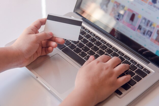 Mano de mujer con tarjeta de crédito y usando laptop haciendo en línea.