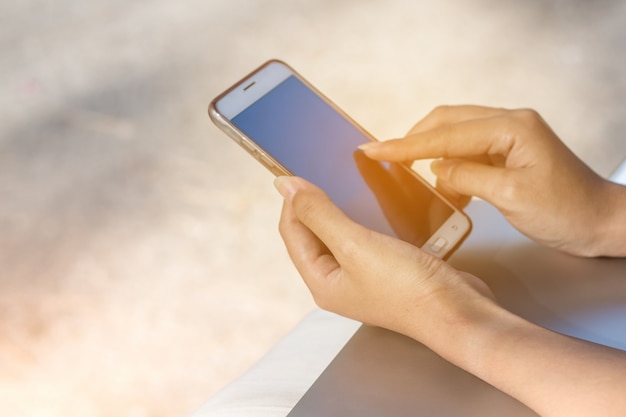 Mano de mujer con teléfono inteligente con pantalla grande en blanco y marco moderno menos diseño