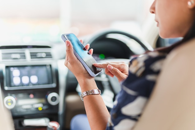 Mano de mujer con teléfono móvil mientras conduce el coche.