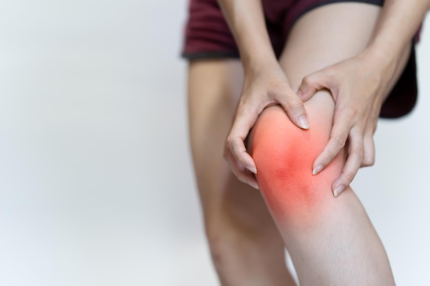 La mano de una mujer toca su rodilla debido al dolor.