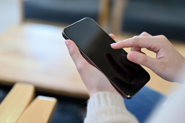 Una mano de mujer tocando o tocando en la pantalla del teléfono inteligente