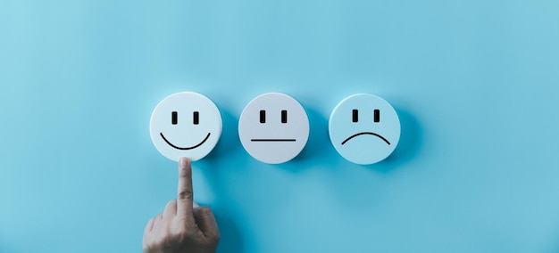 La mano de la mujer tocando el rostro feliz sonríe el icono de la cara en el objeto azul redondo la experiencia del cliente y el servicio con satisfacción concepto de pensamiento positivo evaluación de la salud mental día mundial de la Salud Mental