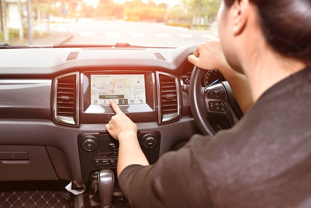 Mano de mujer tocando el sistema multimedia de pantalla con aplicación de navegación GPS.