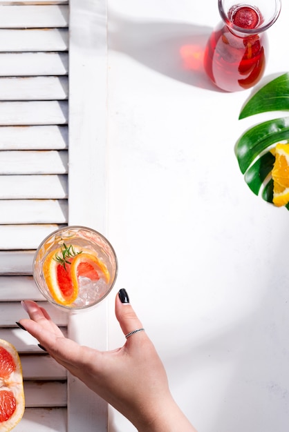 Foto la mano de la mujer toma una bebida fría de verano en un vaso con una rodaja de pomelo