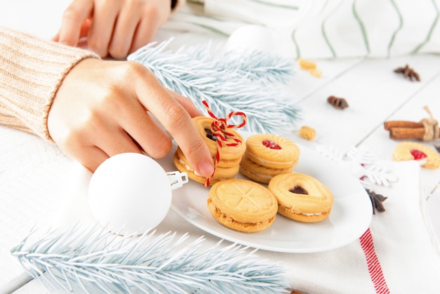 Mano de mujer tomando galletas de plato blanco