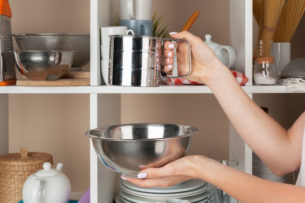 Mano de mujer tomando piezas de vajilla del estante en la cocina