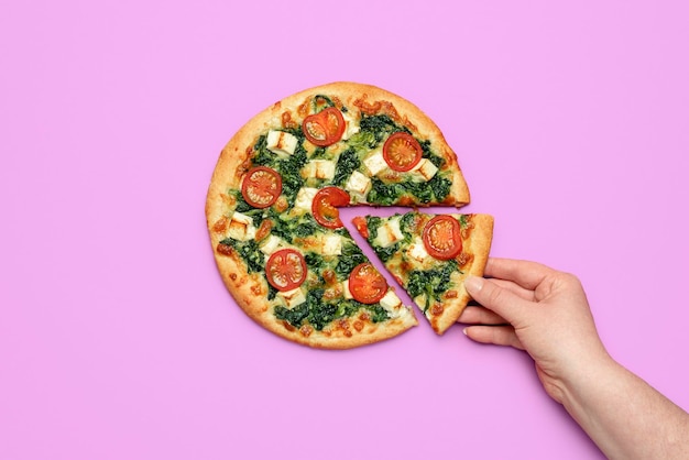 Mano de mujer tomando una rebanada de pizza Pizza vegetariana casera con espinacas y queso feta