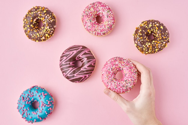 Mano de mujer tomar color donut en rosa