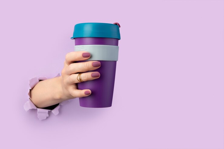 Foto la mano de la mujer a través de un agujero en el papel sostiene un vaso reutilizable. vida ecológica. concepto de desperdicio cero. para llevar, beber café, té para llevar