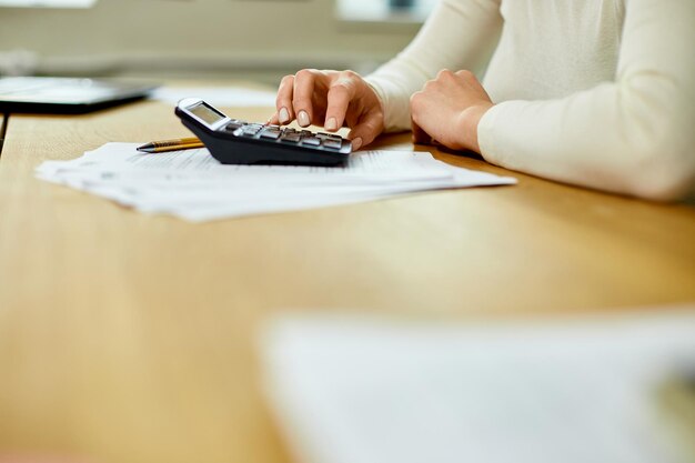 Mano de mujer usando calculadora para calcular facturas domésticas en casa