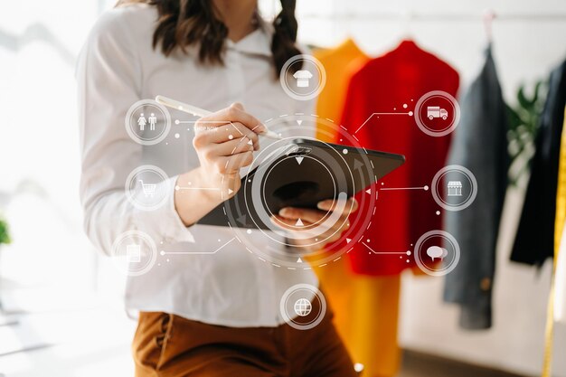 Foto la mano de la mujer usando un portátil, un teléfono inteligente y una tableta y escribiendo un cuaderno en la oficina de su negocio de compras en línea en casa con un icono virtual