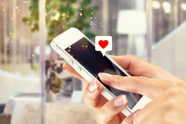 Foto la mano de la mujer usando el teléfono inteligente con el icono del corazón