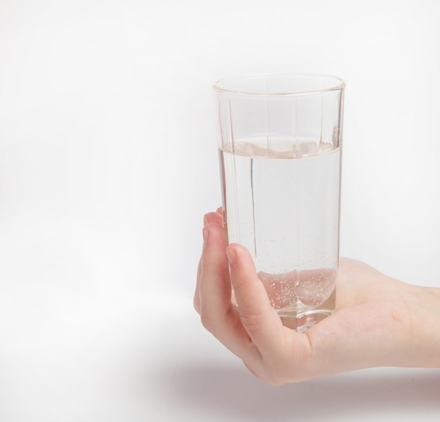 Foto mano de mujer con vaso de agua aislado sobre fondo blanco.