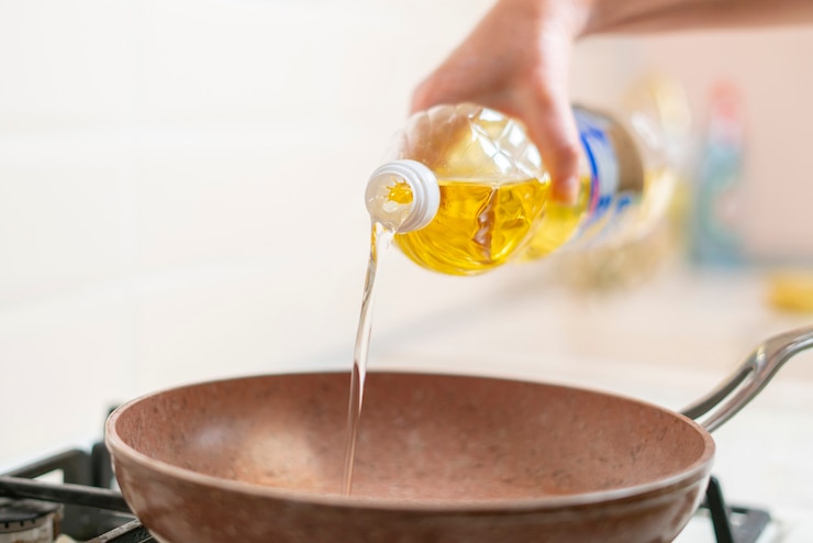 Foto una mano de mujer vierte aceite de cocina en la sartén en casa