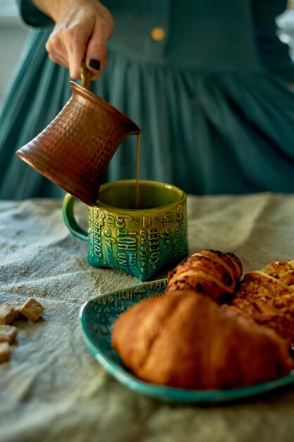 La mano de una mujer vierte café elaborado con sencillez turca rústica