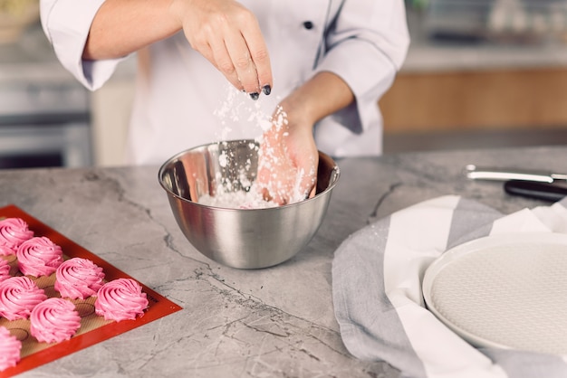 La mano de una mujer vierte harina en un plato. Preparación de malvavisco.