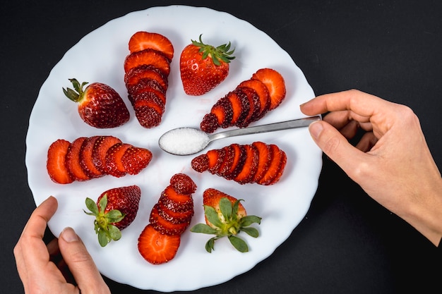 Foto la mano de una mujer en una vista aérea de fresas naturales en un plato blanco