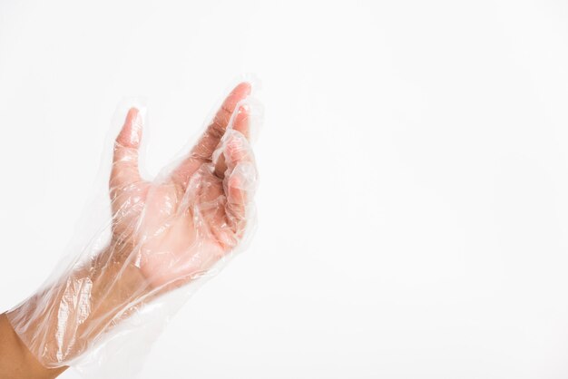 Mano de mujer vistiendo guantes de plástico transparente desechables de protección de un solo uso