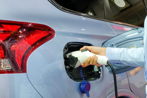 Mano de mujeres alimentando un nuevo vehículo a través de una máquina recargable de electricidad.