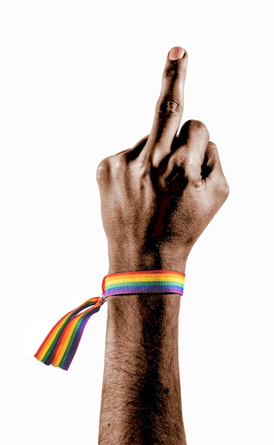 Mano negra con una pulsera con los colores de la bandera LGBT mostrando el dedo medio